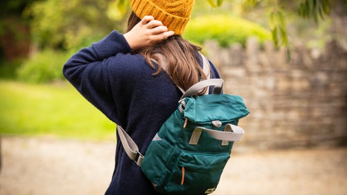 A woman wears a marine colour ROKA rucksack